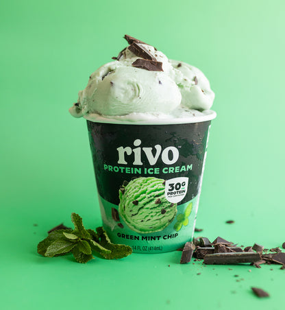 Rivo Green Mint Chip protein ice cream cup with mint leaves and chocolate pieces on a green background