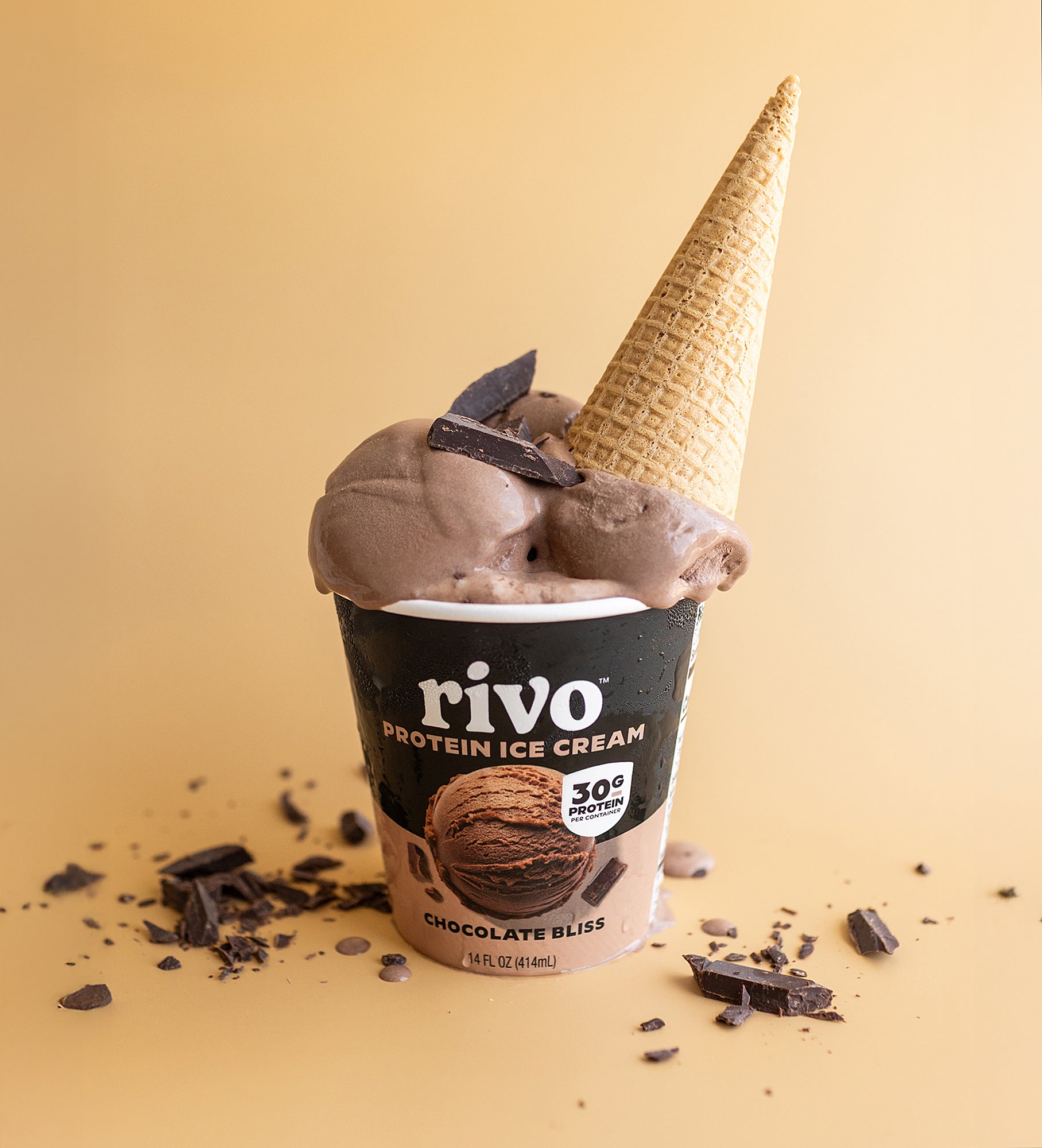 Rivo Chocolate Bliss Protein Ice Cream in a cup with a waffle cone on a beige background